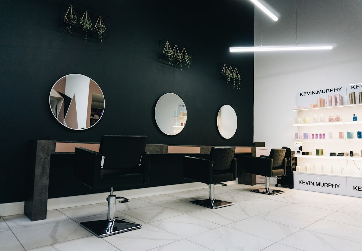 Black salon chairs facing circular mirrors